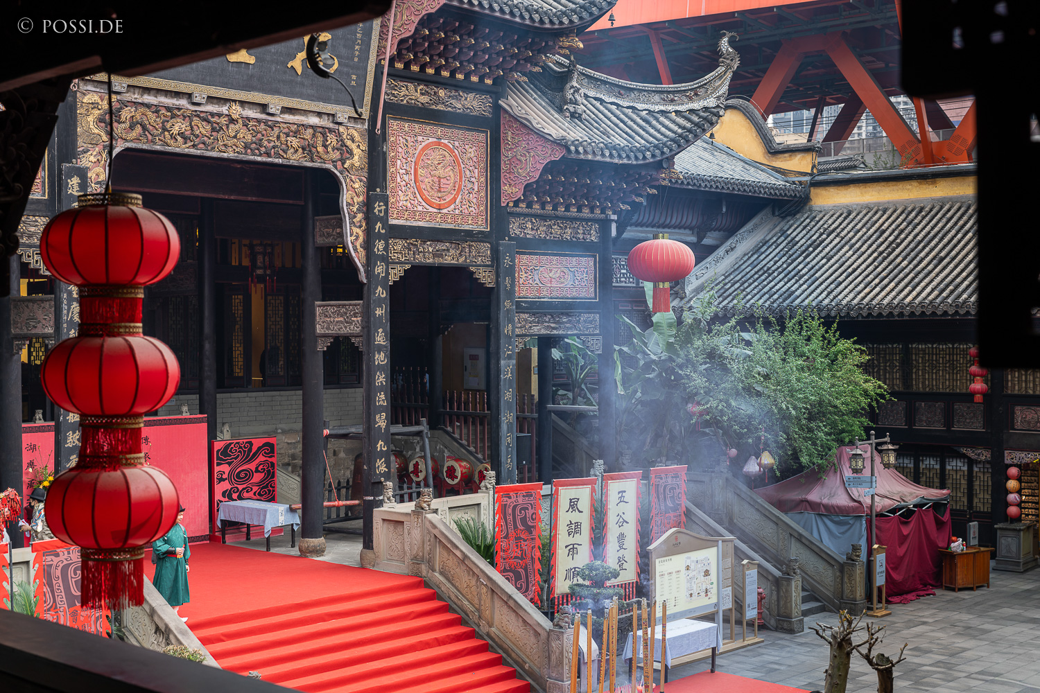 Das Bild zeigt eine chinesische Tempelanlage mit roten Laternen und einem roten Teppich, der zu einer Treppe führt. (03.04.2025)